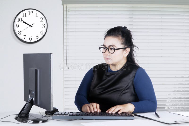 Giovane donna che digita sulla tastiera in ufficio immagini stock libere da diritti