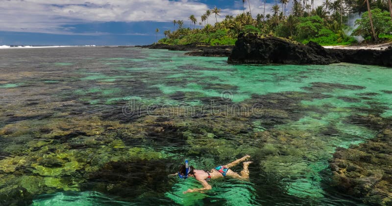 Giovane donna che si immerge sopra la barriera corallina su un'isola tropicale