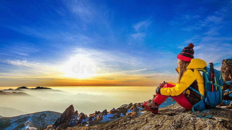 Giovane donna che si siede sulla collina delle alte montagne fotografia stock Giovane donna che si siede sulla collina delle alte montagne fotografia stock
