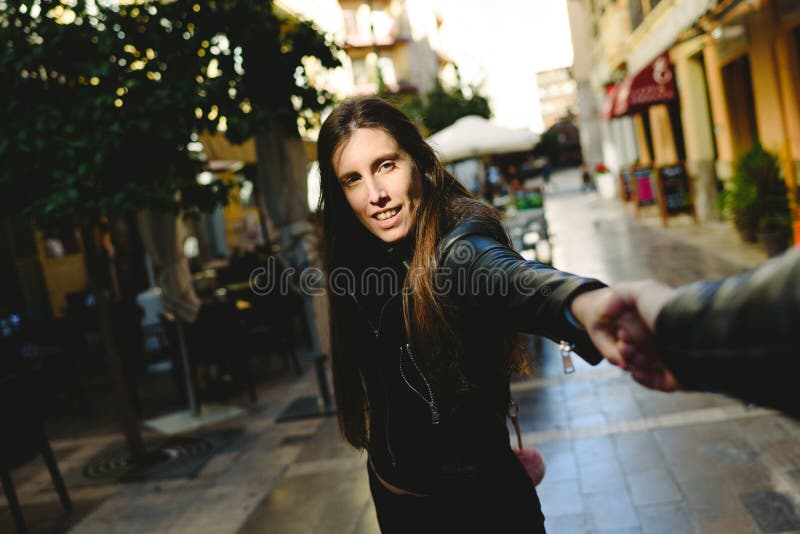 Giovane donna che tiene il braccio del fidanzato mentre la allontana dai negozi per evitare di cadere nel consumismo