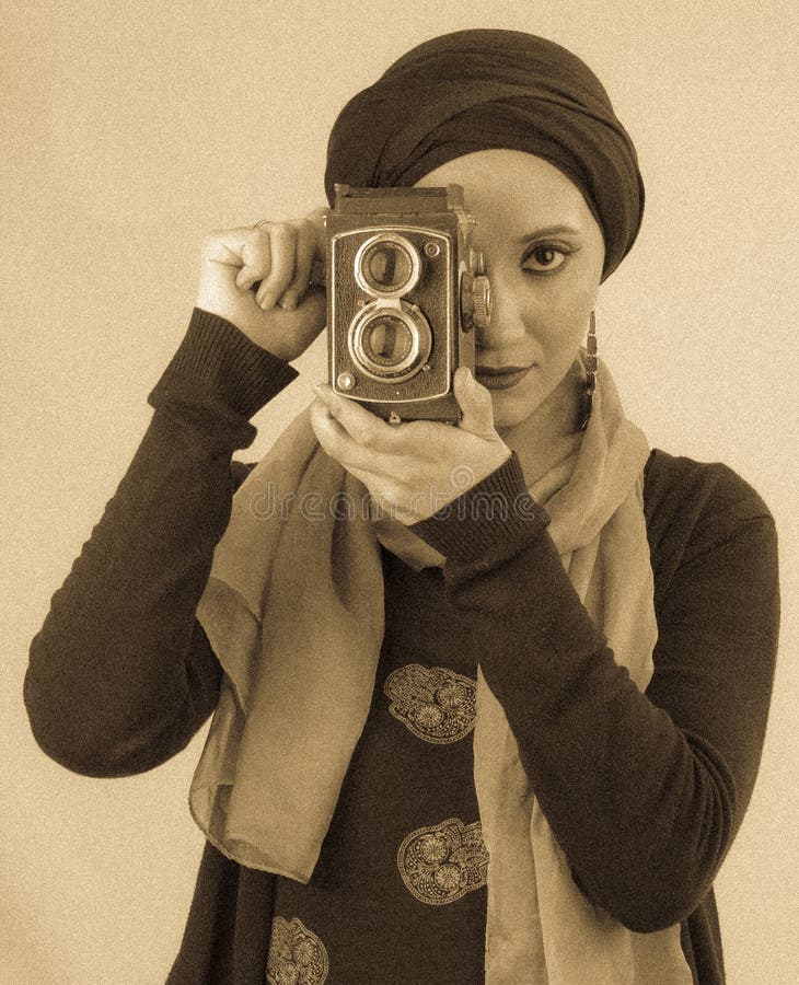 Giovane donna che tiene vecchia macchina fotografica in hijab e sciarpa variopinta fotografia stock Giovane donna che tiene vecchia macchina fotografica in hijab e sciarpa variopinta fotografia stock