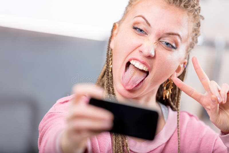 Giovane donna che tira un fronte sciocco per un selfie immagine stock libera da diritti Giovane donna che tira un fronte sciocco per un selfie immagine stock libera da diritti