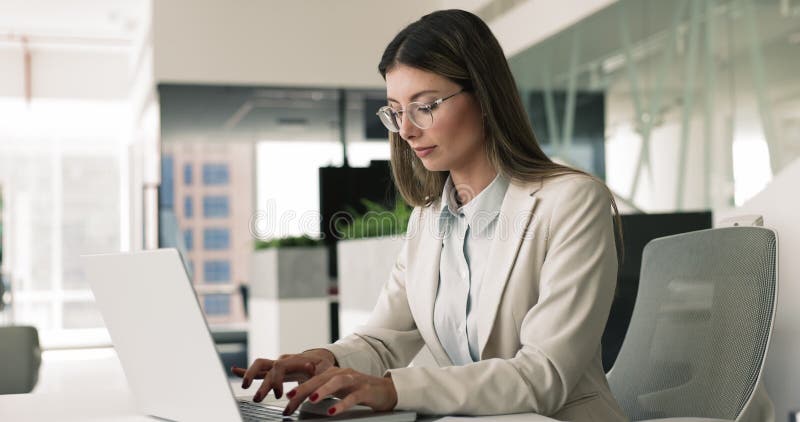Giovane donna che usa il computer portatile nel moderno posto di lavoro archivi video