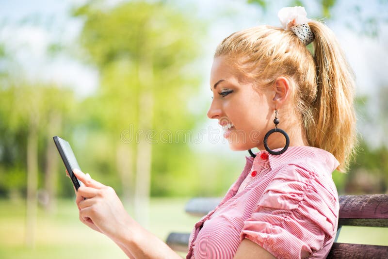 Giovane donna che utilizza compressa digitale nel parco immagini stock libere da diritti Giovane donna che utilizza compressa digitale nel parco immagini stock libere da diritti