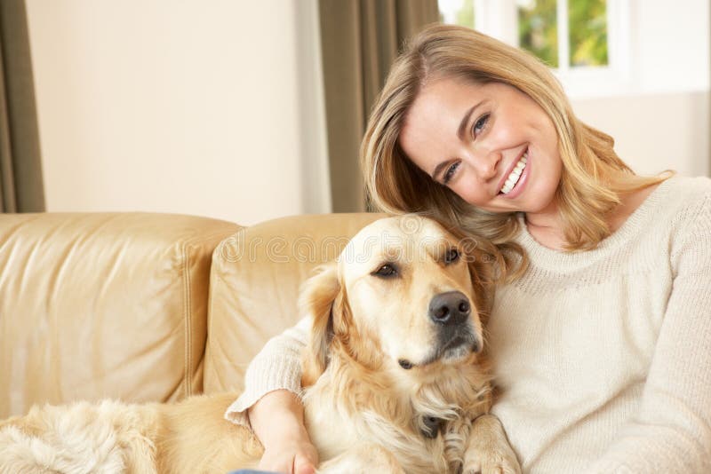 Giovane donna con il cane che si siede sul sofà fotografia stock Giovane donna con il cane che si siede sul sofà fotografia stock