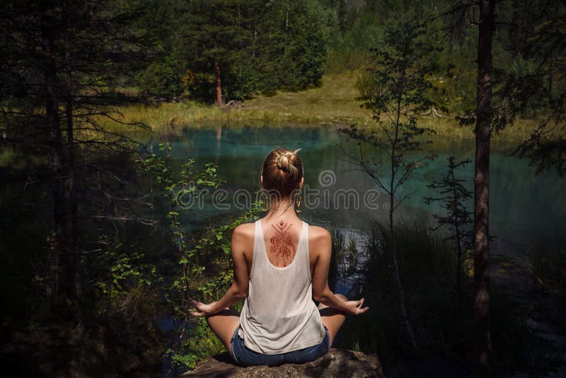 Giovane donna con il mehendi sul suo indietro meditare vicino al mounta blu immagine stock libera da diritti Giovane donna con il mehendi sul suo indietro meditare vicino al mounta blu immagine stock libera da diritti