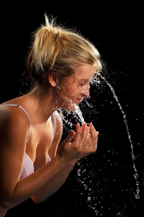 Portrait of beautiful young woman with drops of water around her face. Close-up portrait on dark background. Portrait of beautiful young woman with drops of water around her face. Close-up portrait on dark background