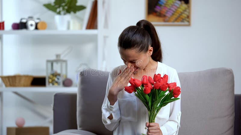Giovane donna con un sacco di tulipani e starnuti, allergia stagionale, salute fotografia stock Giovane donna con un sacco di tulipani e starnuti, allergia stagionale, salute fotografia stock