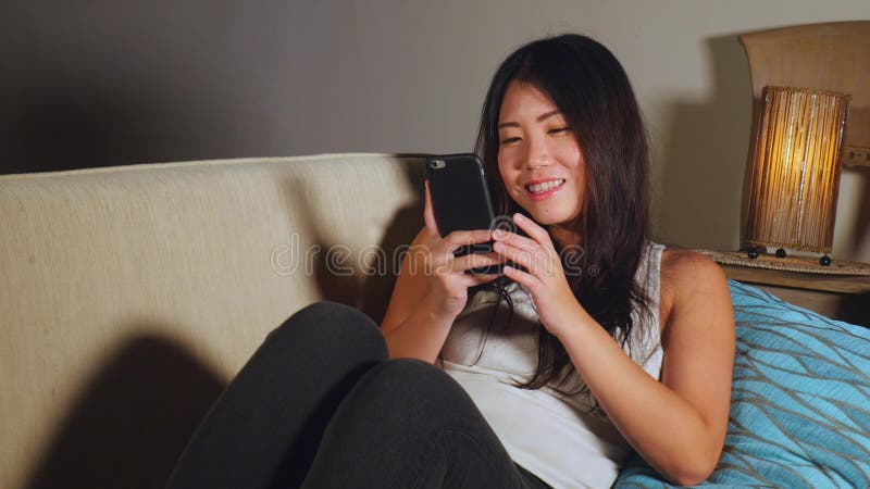 Giovane donna coreana felice ed abbastanza asiatica dolce che usando media sociali app di Internet sul divertiresi allegro sorrid immagine stock libera da diritti Giovane donna coreana felice ed abbastanza asiatica dolce che usando media sociali app di Internet sul divertiresi allegro sorrid immagine stock libera da diritti