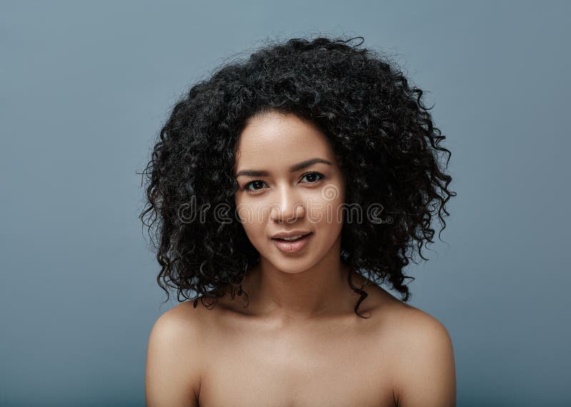 Giovane donna dai capelli ricci neri che guarda la telecamera fotografia stock