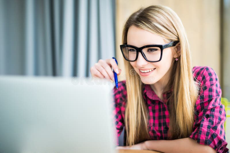 Giovane donna del concentrato che esamina lo schermo del computer portatile immagine stock libera da diritti Giovane donna del concentrato che esamina lo schermo del computer portatile immagine stock libera da diritti