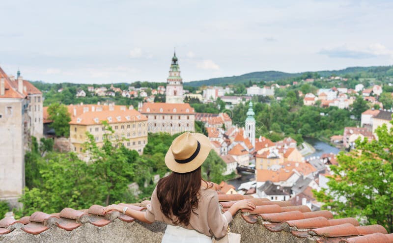 Giovane donna del viaggiatore in cappello che esamina vista della città di Cesky Krumlov, repubblica Ceca di estate fotografia stock Giovane donna del viaggiatore in cappello che esamina vista della città di Cesky Krumlov, repubblica Ceca di estate fotografia stock