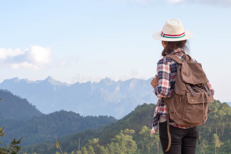 Giovane donna del viaggiatore con lo zaino alla moda che osserva in avanti il Mountain View di stupore Godere della natura, si ri fotografia stock Giovane donna del viaggiatore con lo zaino alla moda che osserva in avanti il Mountain View di stupore Godere della natura, si ri fotografia stock