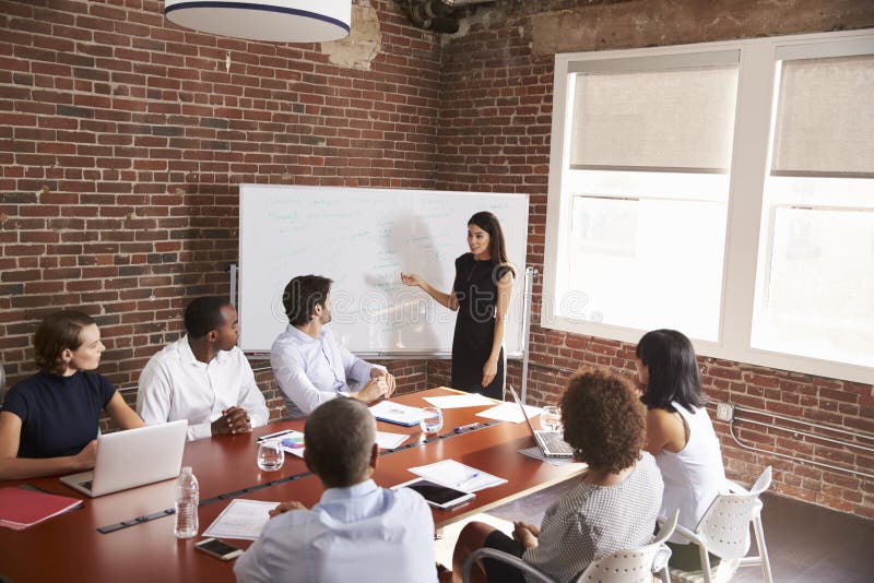 Giovane donna di affari Addressing Boardroom Meeting fotografie stock libere da diritti Giovane donna di affari Addressing Boardroom Meeting fotografie stock libere da diritti