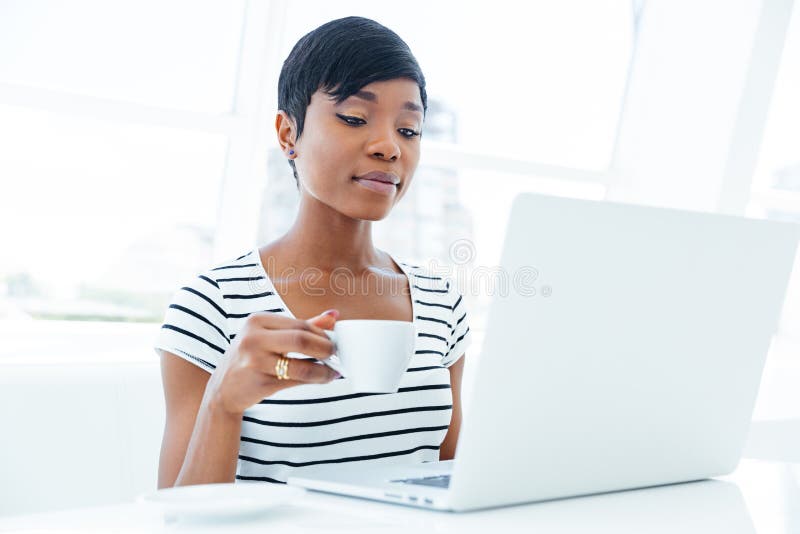 Giovane donna di affari afroamericana pensierosa che si siede nel luogo di lavoro immagine stock libera da diritti Giovane donna di affari afroamericana pensierosa che si siede nel luogo di lavoro immagine stock libera da diritti