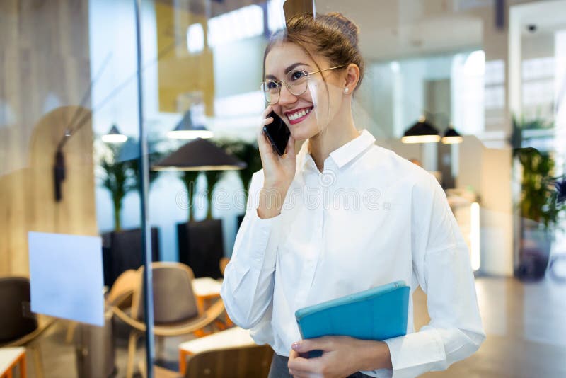 Giovane donna di affari alla moda che parla con il suo telefono cellulare mentre tenendo la sua condizione digitale della compres fotografie stock libere da diritti Giovane donna di affari alla moda che parla con il suo telefono cellulare mentre tenendo la sua condizione digitale della compres fotografie stock libere da diritti