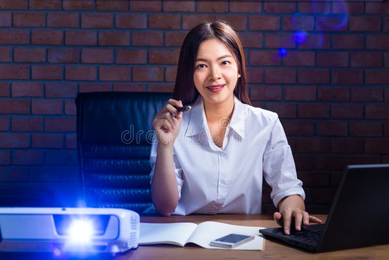 Giovane donna di affari asiatica in camicia di colore del ligth che funziona tardi nella h immagine stock libera da diritti Giovane donna di affari asiatica in camicia di colore del ligth che funziona tardi nella h immagine stock libera da diritti