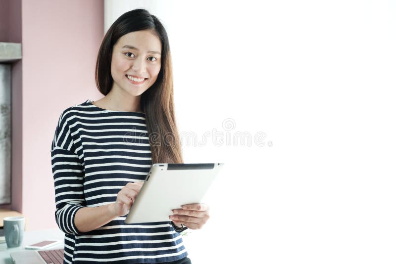 Giovane donna di affari asiatica che per mezzo della compressa con il fronte sorridente, positi fotografie stock Giovane donna di affari asiatica che per mezzo della compressa con il fronte sorridente, positi fotografie stock