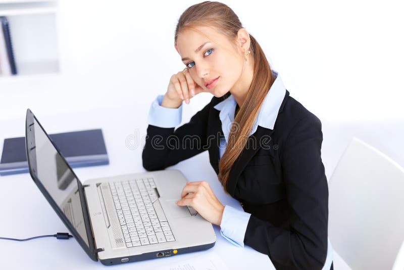 Giovane donna di affari che lavora al computer portatile in ufficio fotografie stock Giovane donna di affari che lavora al computer portatile in ufficio fotografie stock