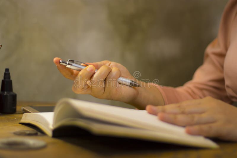 Giovane donna di affari che lavora con una penna all'ufficio, lei che resta fuori orario immagini stock libere da diritti Giovane donna di affari che lavora con una penna all'ufficio, lei che resta fuori orario immagini stock libere da diritti