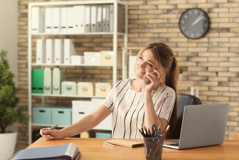 Giovane donna di affari che parla sul telefono cellulare in ufficio fotografie stock Giovane donna di affari che parla sul telefono cellulare in ufficio fotografie stock