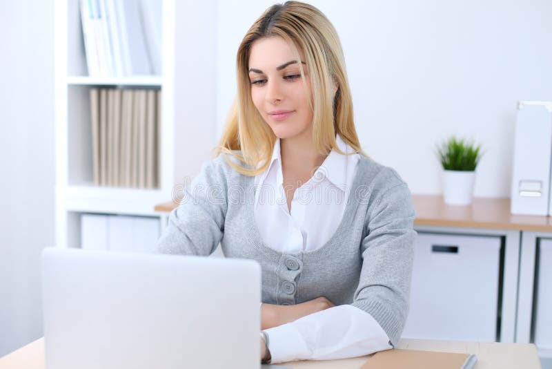 Giovane donna di affari o ragazza dello studente che si siede nel luogo di lavoro dell'ufficio con il computer portatile Concetto immagini stock libere da diritti Giovane donna di affari o ragazza dello studente che si siede nel luogo di lavoro dell'ufficio con il computer portatile Concetto immagini stock libere da diritti