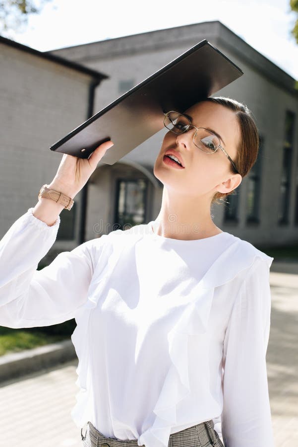 Giovane donna di affari in usura convenzionale e vetri che si proteggono da luce solare luminosa immagine stock Giovane donna di affari in usura convenzionale e vetri che si proteggono da luce solare luminosa immagine stock