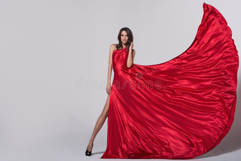 Giovane donna di bellezza in vestito rosso d'ondeggiamento fotografia stock libera da diritti Giovane donna di bellezza in vestito rosso d'ondeggiamento fotografia stock libera da diritti