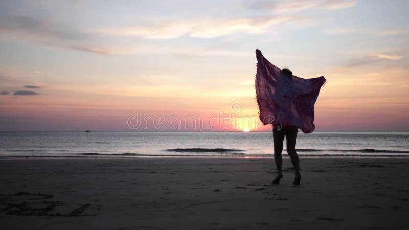 Giovane donna di estate con sciarpa che si gode una vacanza al tramonto sulla spiaggia tropicale