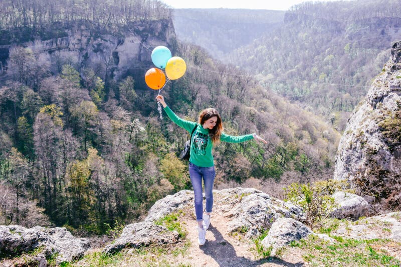 Giovane donna divertendosi con i palloni colorati sull'orlo della scogliera in montagne russe immagini stock libere da diritti Giovane donna divertendosi con i palloni colorati sull'orlo della scogliera in montagne russe immagini stock libere da diritti