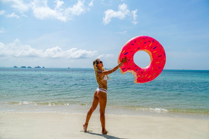 Giovane donna divertendosi con l'anello gonfiabile sulla spiaggia fotografia stock Giovane donna divertendosi con l'anello gonfiabile sulla spiaggia fotografia stock
