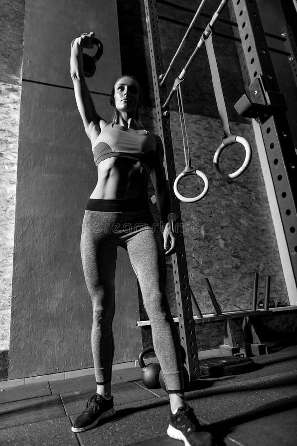 Giovane donna esile che solleva un kettlebell immagini stock Giovane donna esile che solleva un kettlebell immagini stock