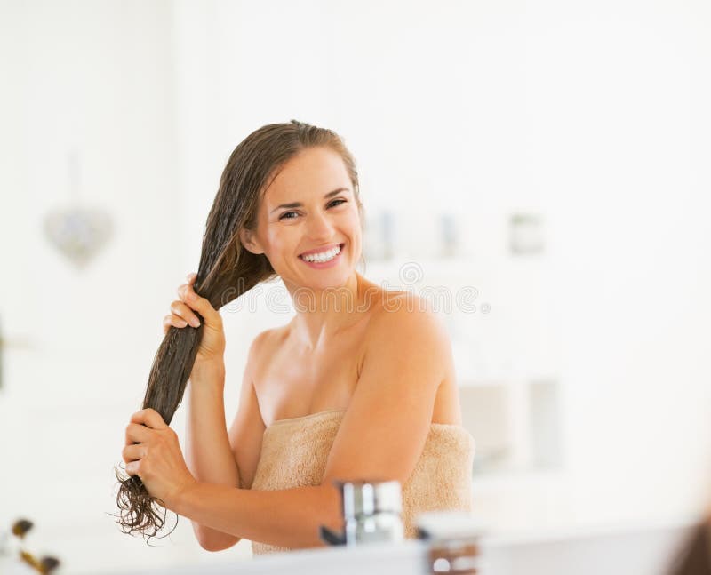 Giovane donna felice che applica la maschera dei capelli in bagno