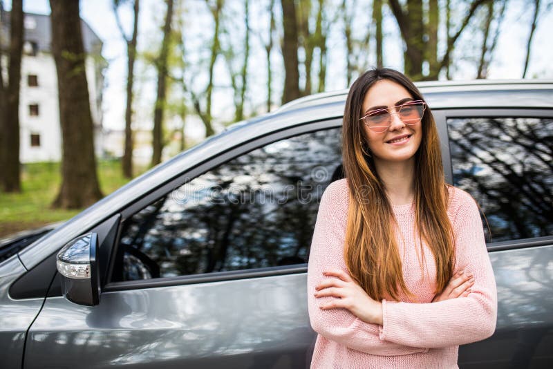 Giovane donna felice che fa una pausa la sua automobile con le mani attraversate immagine stock Giovane donna felice che fa una pausa la sua automobile con le mani attraversate immagine stock
