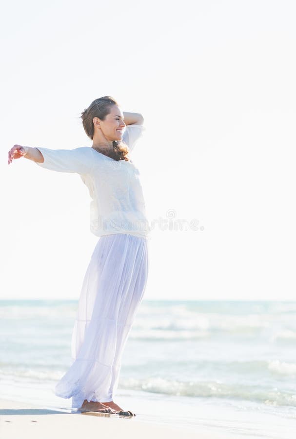Giovane donna felice che si rilassa alla spiaggia fotografia stock Giovane donna felice che si rilassa alla spiaggia fotografia stock