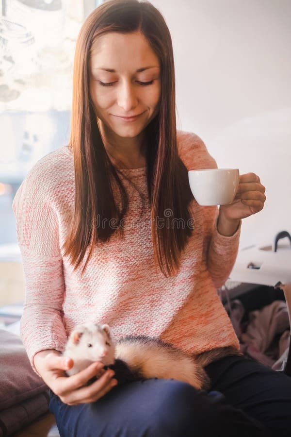 Giovane donna felice ed il suo furetto dell'animale domestico in caffè immagine stock libera da diritti Giovane donna felice ed il suo furetto dell'animale domestico in caffè immagine stock libera da diritti