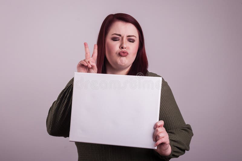 Young white female holding a blank empty whiteboard sign puckering libs gesturing a peace sign eyes closed. Young white female holding a blank empty whiteboard sign puckering libs gesturing a peace sign eyes closed