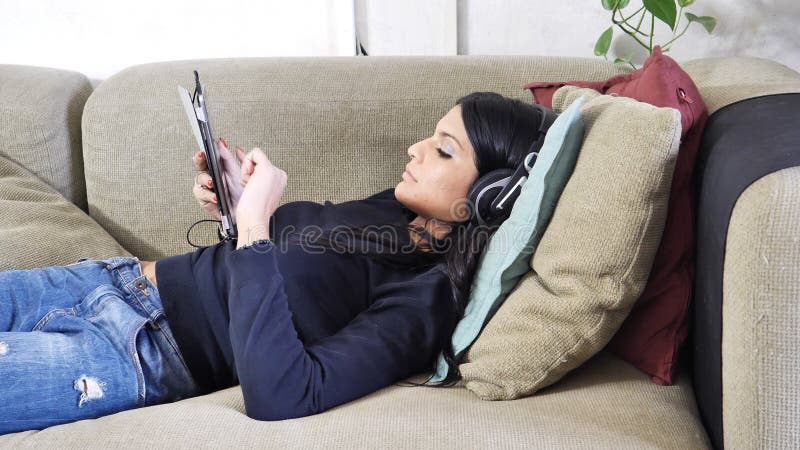 Giovane donna graziosa che ascolta la musica con le cuffie fotografia stock Giovane donna graziosa che ascolta la musica con le cuffie fotografia stock