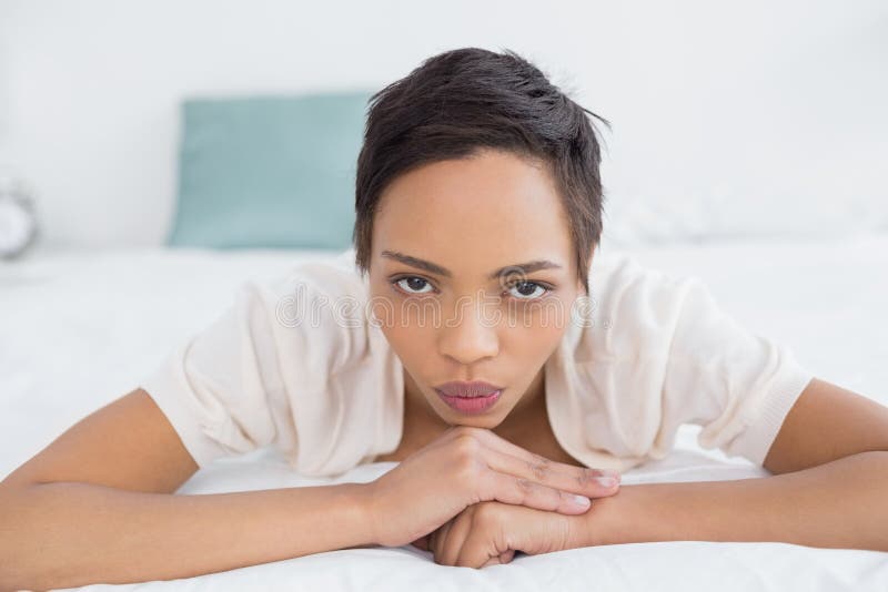 Giovane donna graziosa seria che si rilassa a letto fotografie stock