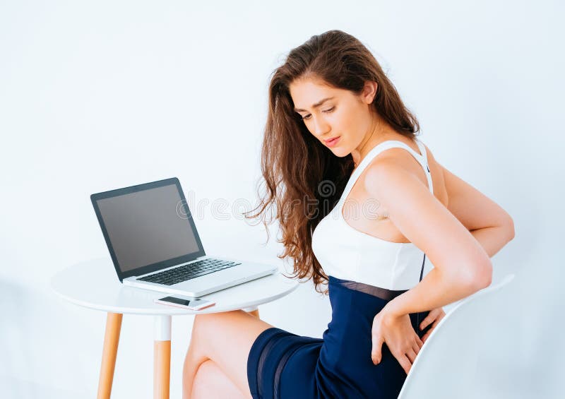 Giovane donna lavorante caucasica di affari sullo scrittorio con la sofferenza del computer portatile più lombo-sacrale ed il dol