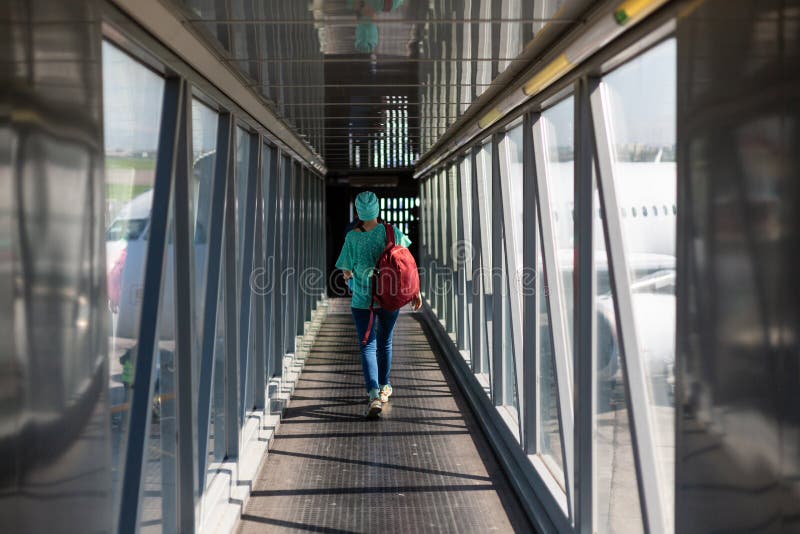 Giovane donna nel ponte di imbarco nell'aeroporto immagini stock libere da diritti Giovane donna nel ponte di imbarco nell'aeroporto immagini stock libere da diritti