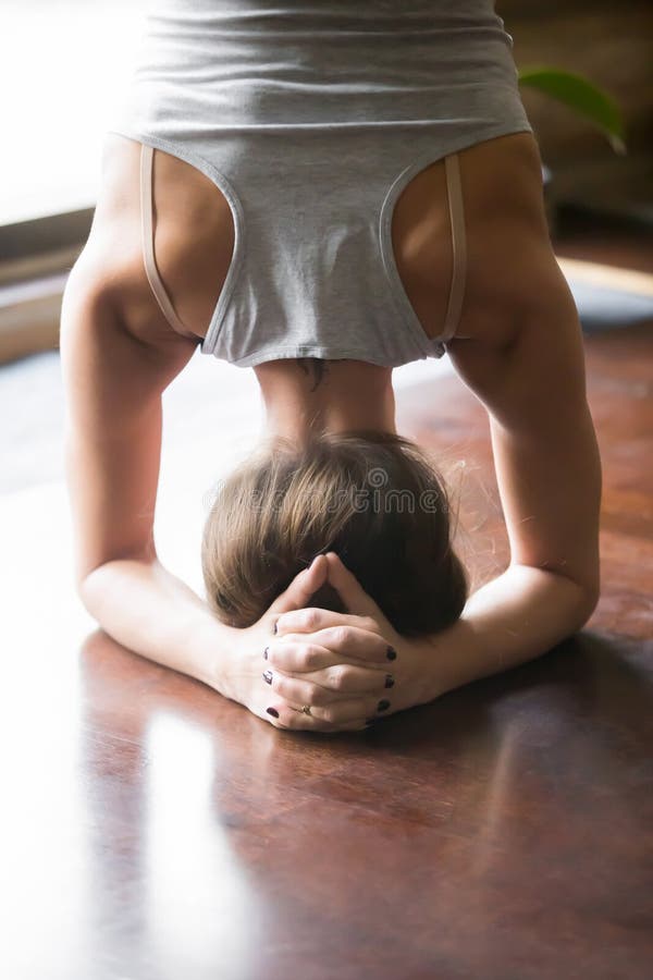 Giovane donna nella posa di sirsasana di salamba, casa, primo piano, retrovisione immagine stock Giovane donna nella posa di sirsasana di salamba, casa, primo piano, retrovisione immagine stock