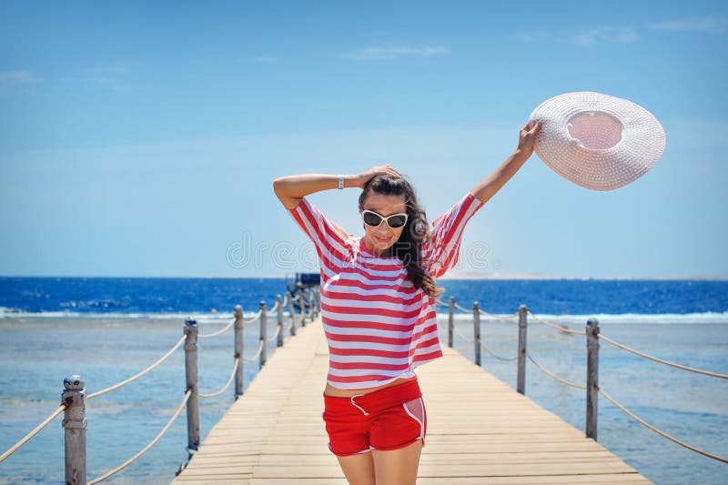 Giovane donna piena di energia su un pontone davanti al mare un giorno soleggiato immagine stock Giovane donna piena di energia su un pontone davanti al mare un giorno soleggiato immagine stock