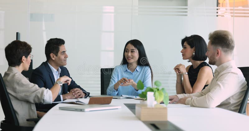 Giovane donna positiva leader del team asiatico parla con colleghi multietnici