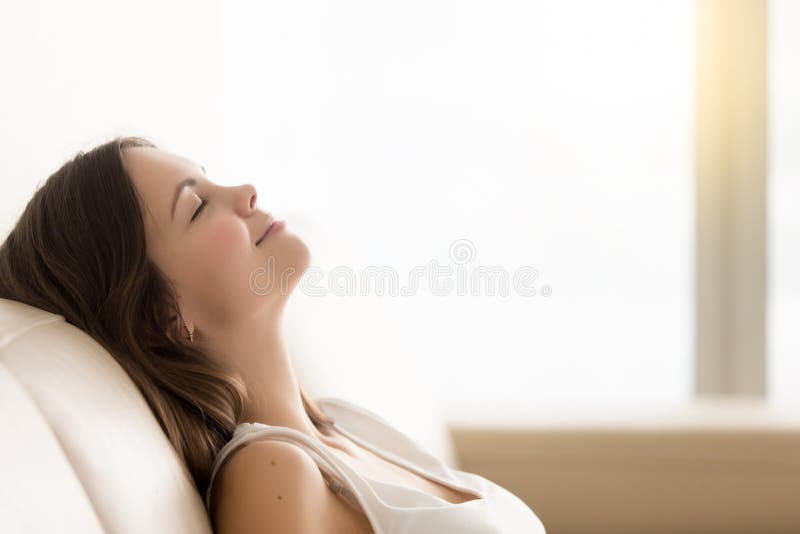 Giovane donna rilassata che gode del resto sul sofà comodo, spac della copia