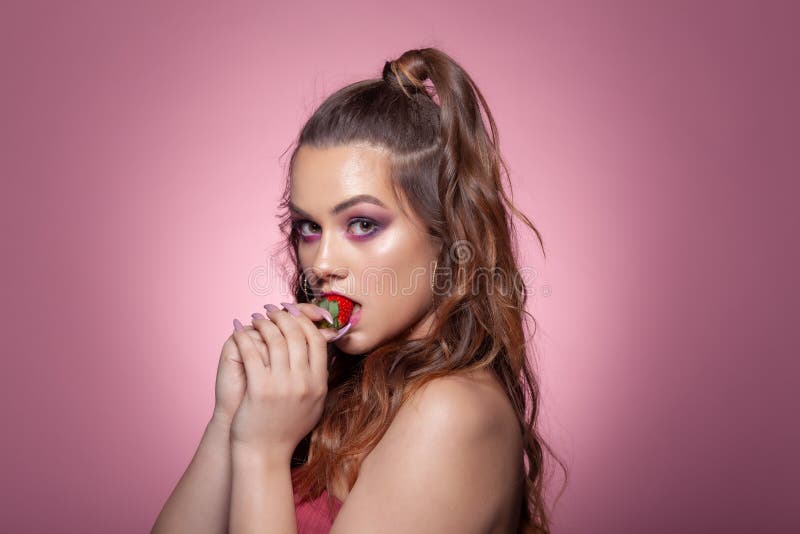 sexy girl holding strawberry with whipped cream isolated on pink