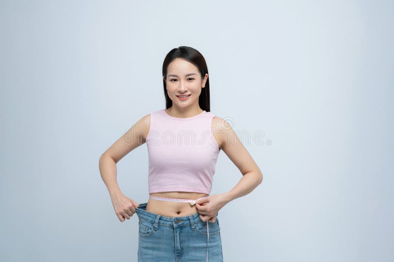 Giovane donna simpatica indossa pantaloni allentati dopo la perdita di peso: nastro in vita immagini stock libere da diritti