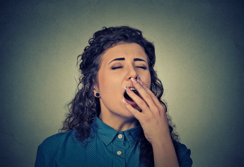 It is too early for meeting. Closeup portrait sleepy young woman with wide open mouth yawning eyes closed looking bored on gray wall background. Face expression emotion body language. It is too early for meeting. Closeup portrait sleepy young woman with wide open mouth yawning eyes closed looking bored on gray wall background. Face expression emotion body language