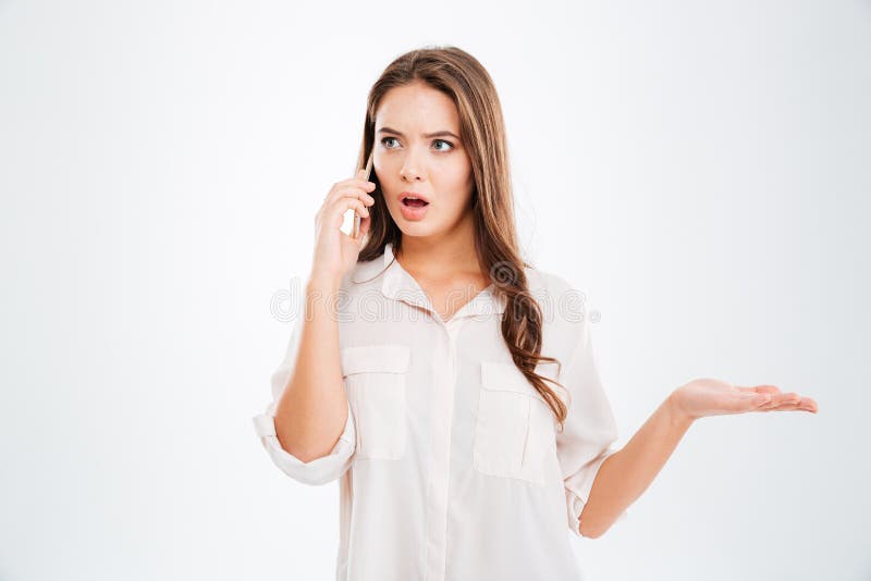 Giovane donna sorpresa che parla sul telefono e che tiene copyspace immagini stock Giovane donna sorpresa che parla sul telefono e che tiene copyspace immagini stock