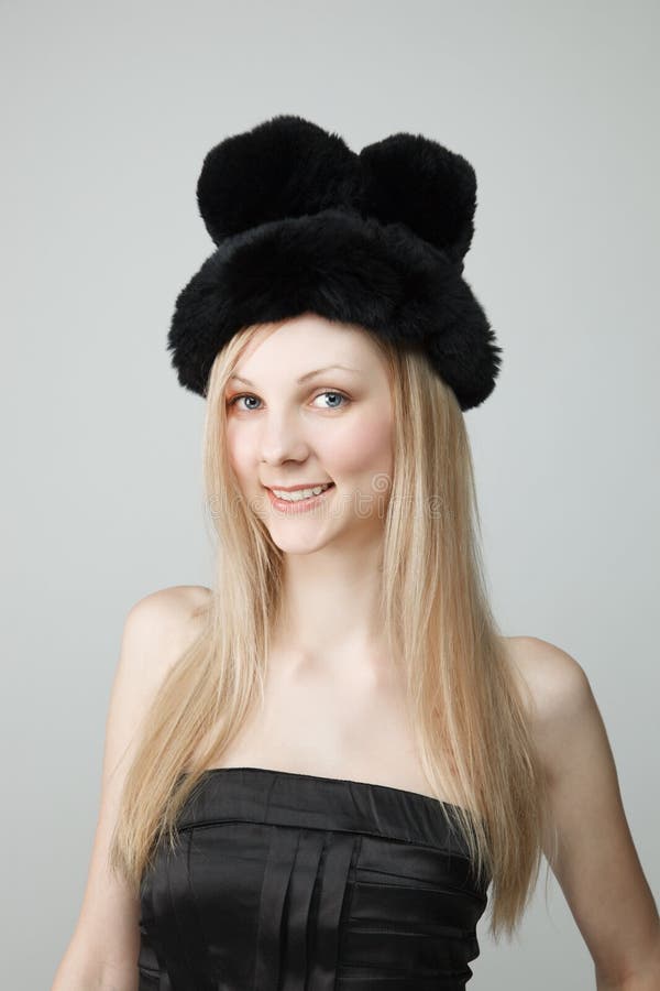 Giovane donna sorridente in cappello di pelliccia fotografia stock Giovane donna sorridente in cappello di pelliccia fotografia stock